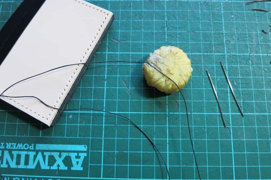 Linen thread being waxed with bees wax