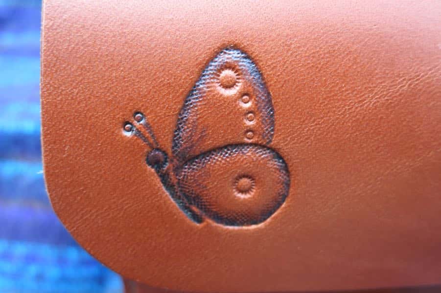 Detail of butterfly motif on small brown leather shoulder bag