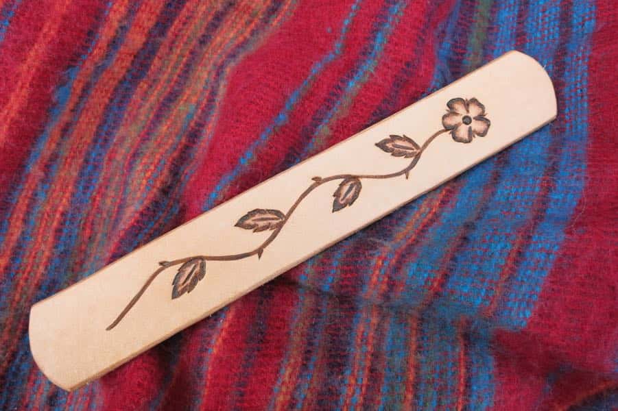 Dog rose motif leather bookmark on red cloth background