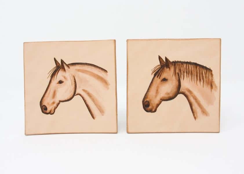 Pair of horse head motif square leather drinks coasters on a white background