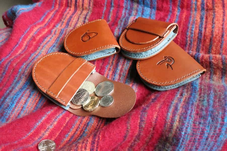 Four small brown leather coin pouches showing plain, butterfly and bird motifs