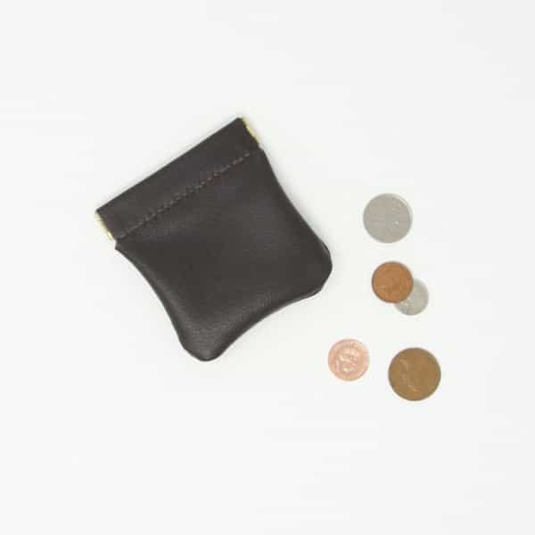 Traditional brown leather snap purse shown next to some coins