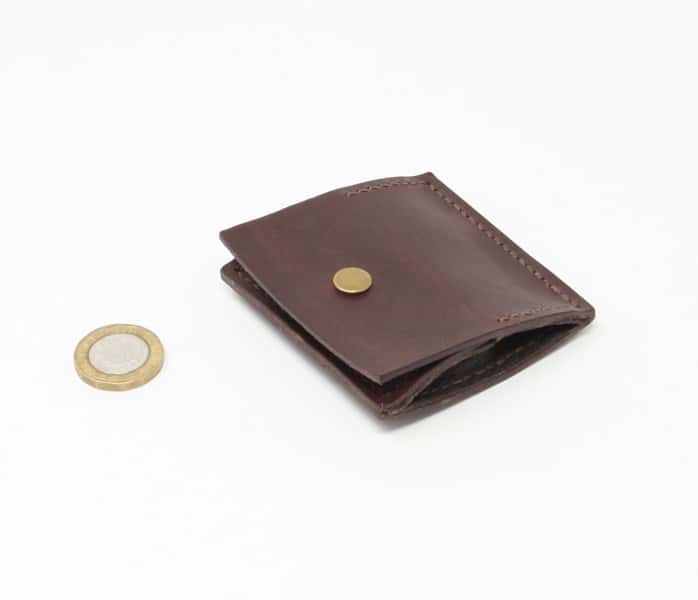 Square brown leather coin purse closed with pound coin for scale