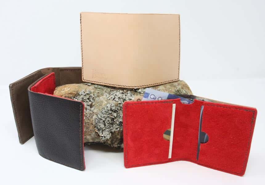 Four slim line leather wallets arranged around a log