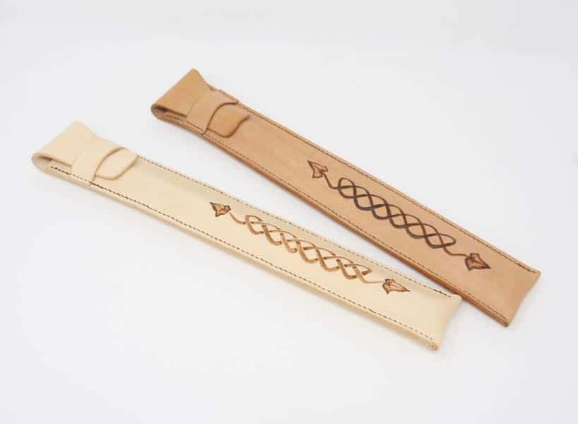 New and aged leather penny whistle cases against white background